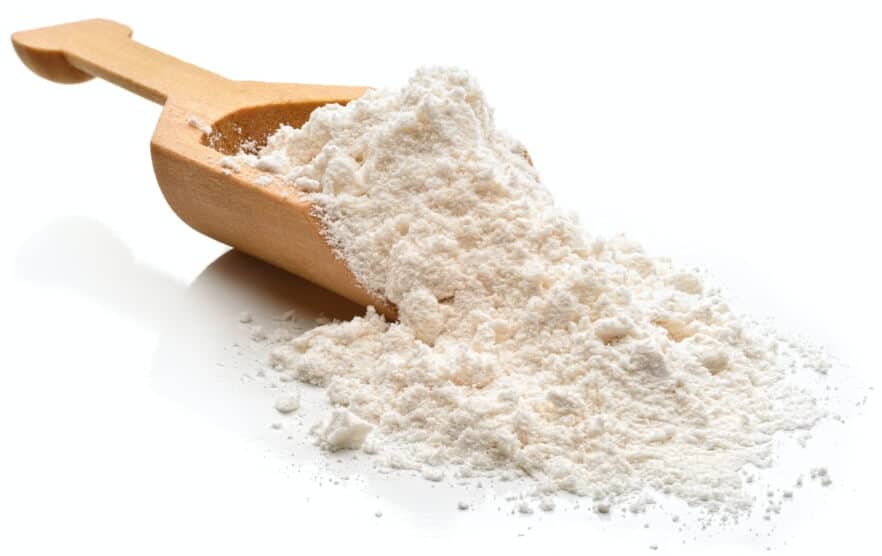 A wooden spoon with flour spilling out of it.