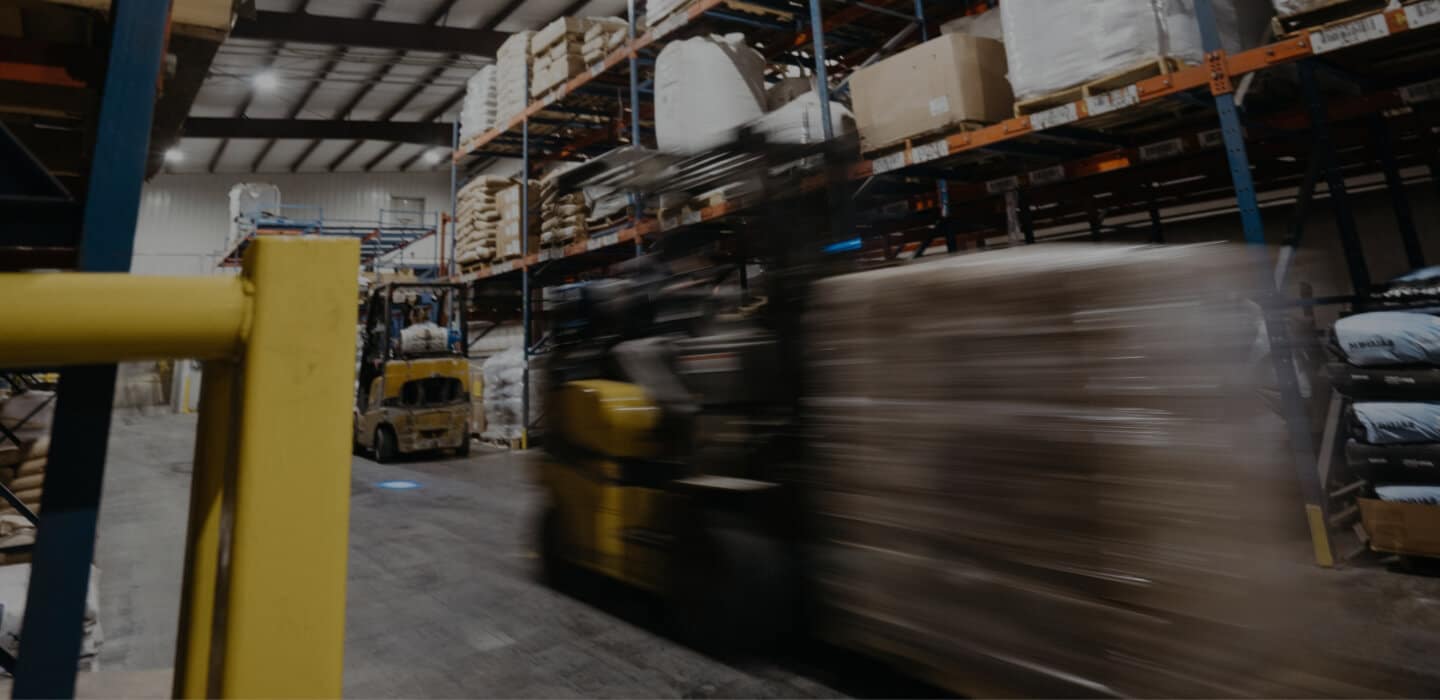 A blurry forklift, showing motion, in a warehouse.